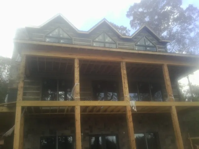 Dormers and porch framing on a large log home under construction — Roof Coating work by our crew in Harrington