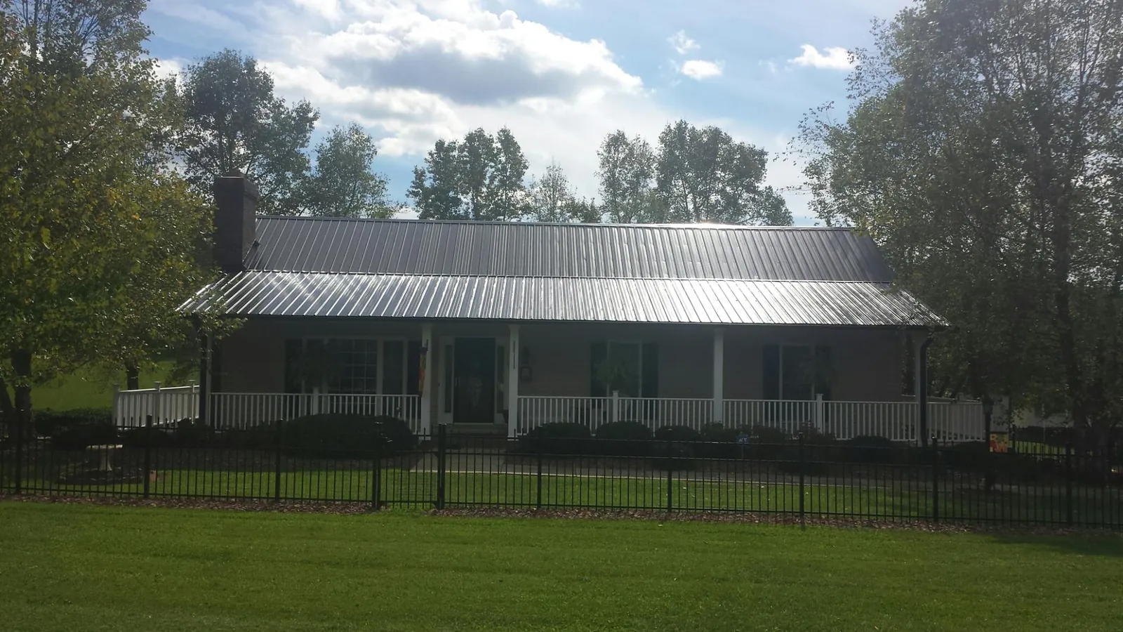 Gray metal roof on a brick ranch with a full width front porch — Gutter Guard Installation work by our crew in Harrington